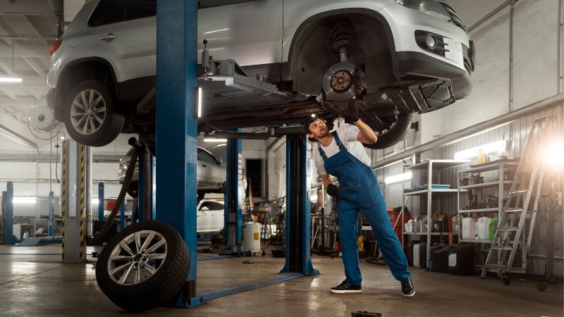 homem consertando um carro em uma oficina mecânica  